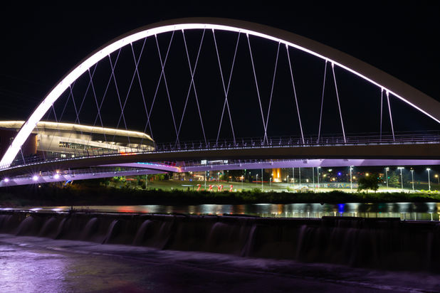 The Iowa Women of Achievement Bridge at night with downtown in the background.