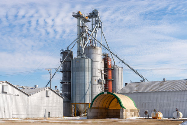 Industrial silos with blue skies and clouds in the background.