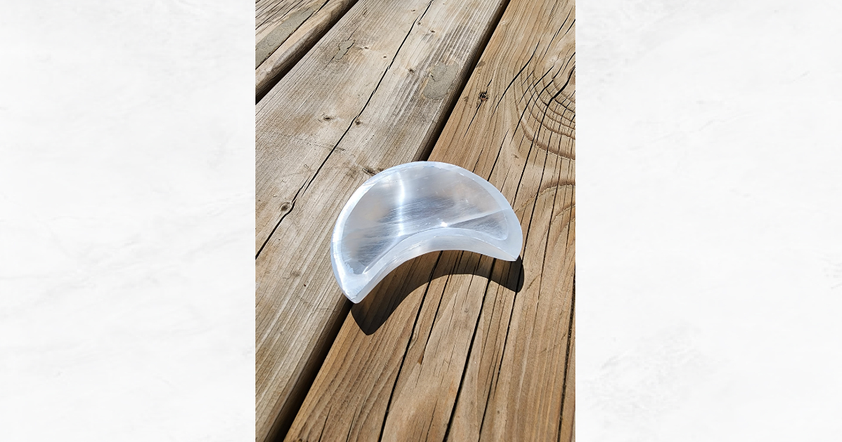 Selenite crescent moon bowl on a wooden surface.