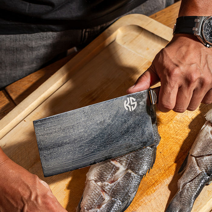 Chef slicing fish with a cleaver on a wooden cutting board, restaurant photography