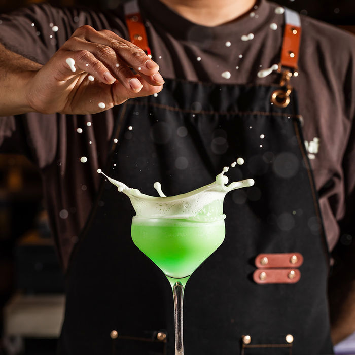 Bartender holding a green cocktail mid-splash, cocktail photography for restaurant client in Portland