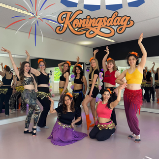 Groepsfoto van buikdansstudenten en instructeur die Koningsdag vieren bij Joy Dance Lab in Eindhoven