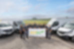 Unser Team steht stolz vor einem Banner mit unserem Logo, umgeben von unseren Firmenfahrzeugen und einer idyllischen Naturkulisse. Die Menschen hinter unseren innovativen Lösungen für eine nachhaltige Zukunft.