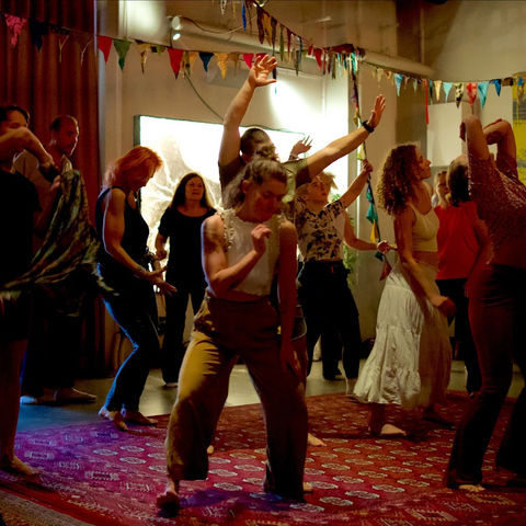 Dancers with their arms up in front of the bright screen