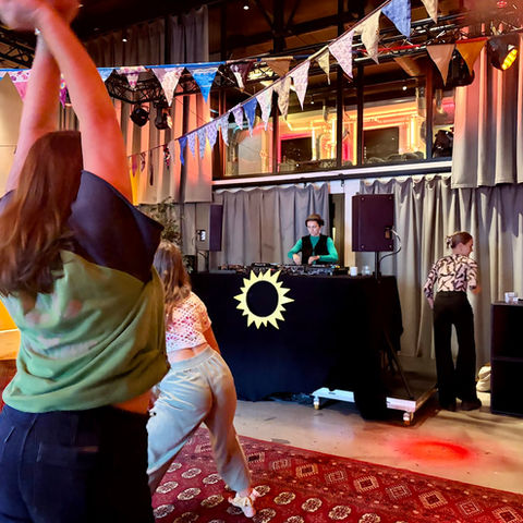 A dancer with an arm raised by the DJ