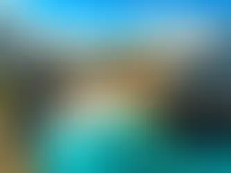 Spiaggia tra le scogliere in un centro storico della Puglia, con mare turchese, bagnanti e case in pietra sullo sfondo.