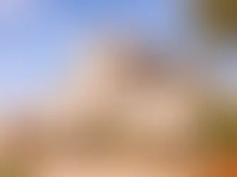 Vista esterna di una masseria in Puglia in pietra chiara, circondata da vasi fioriti e ulivi, immagine che racconta l’autenticità del turismo rurale e il fascino della struttura.