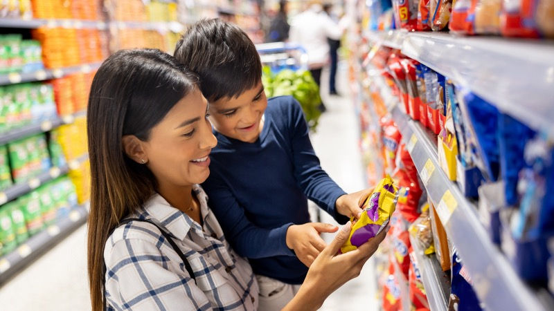 Mother and son reading a food product label in a store.