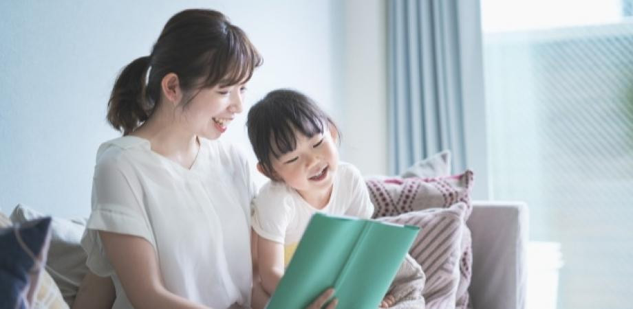 ソファに座って一緒に本を読む母と子