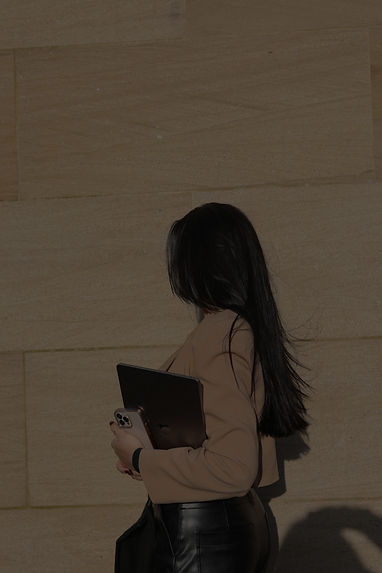 Girl with long dark hair holding a phone and laptop