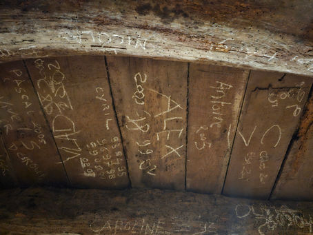 Chalk names and years etched into wooden cellar beams at a Pouilly-Fuissé domaine in Burgundy, France
