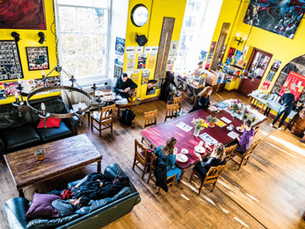 People sitting around a table viewed for above eating breakfast in the main lounge at Castle Rock Hostel.