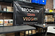 Brooklyn Supported Agriculture's distribution space with a Brooklyn Loves Veggies banner and stacked produce crates