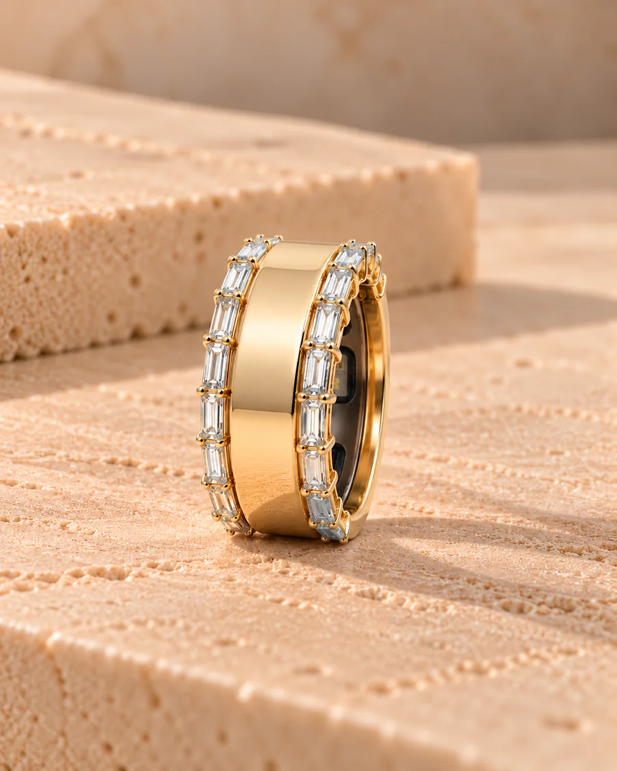 HALO Baguette in 14k yellow gold with two rows of baguette diamonds, worn over an Oura Ring, standing on sandstone