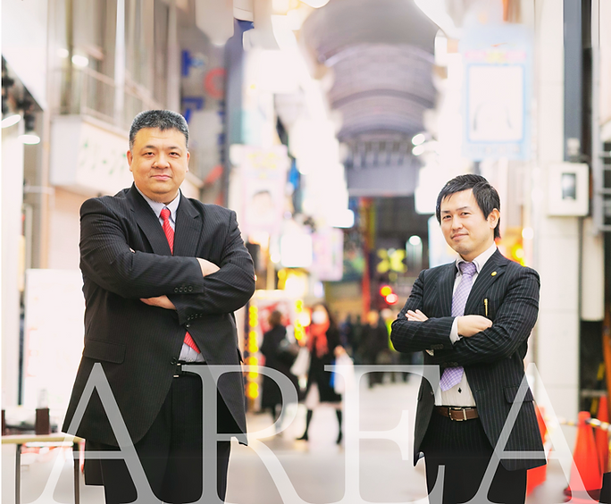 弊社代表が商店街をバックに立っている