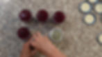 Hands sealing jars of red jam on a speckled counter, surrounded by lids. Jars arranged in a row, creating a neat and organized setting.