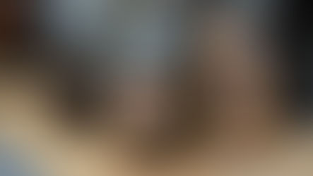 Glass jar with a metal lid containing dried orange slices, placed on a wooden surface. Background shows more jars with similar slices.