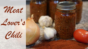 Jars of chili with onion, garlic, tomato, and chili powder on a countertop. Text reads "Meat Lover's Chili." Rustic kitchen vibe.