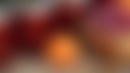 Jars of red jam, an apricot, and a wooden bowl of raspberries on a woven surface, creating a fresh and inviting scene.