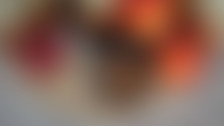 Jars of nectarine jam, fresh nectarines, and a small bowl with a spoon on a woven mat on a granite countertop, creating a homely feel.