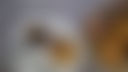 Tea in a floral cup with a bag, served with sugar-coated and plain donuts on a plate. Marble background, casual setting.