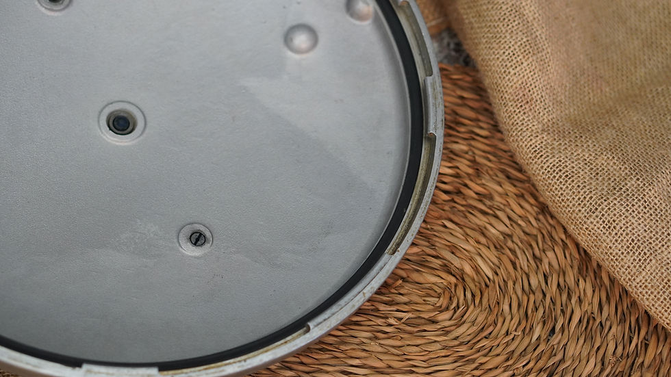 Pressure Canner lid on woven mat, with burlap fabric partly visible. Industrial appearance with a neutral color palette.