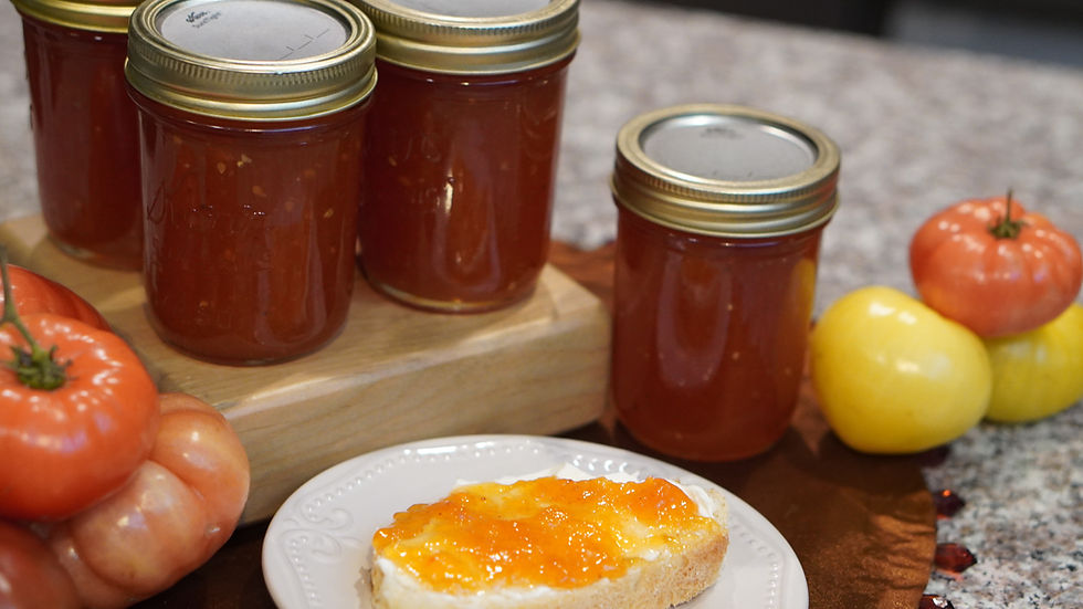 Jars of tomato preserves and fresh tomatoes on a wooden board. A slice of bread with jam rests on a white plate. Warm kitchen setting.