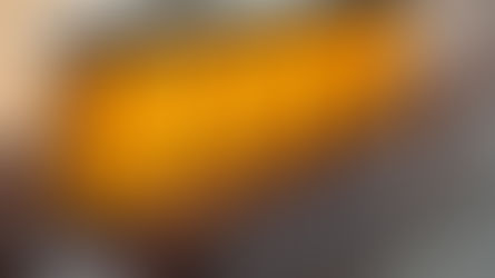 Jars of golden honey with silver lids line a wooden tray, lit warmly. Geometric patterns adorn the glass in a cozy kitchen setting.