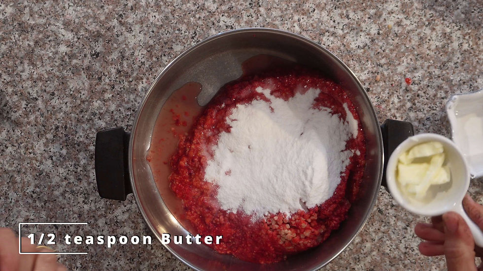 Steel pot with red mixture and white powder on granite counter. Hand holds a cup with butter. Text: "1/2 teaspoon Butter."