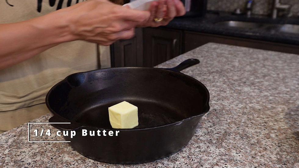 Hands holding paper near a black skillet on a granite countertop. A 1/4 cup of butter is inside the skillet. Text reads "1/4 cup Butter".