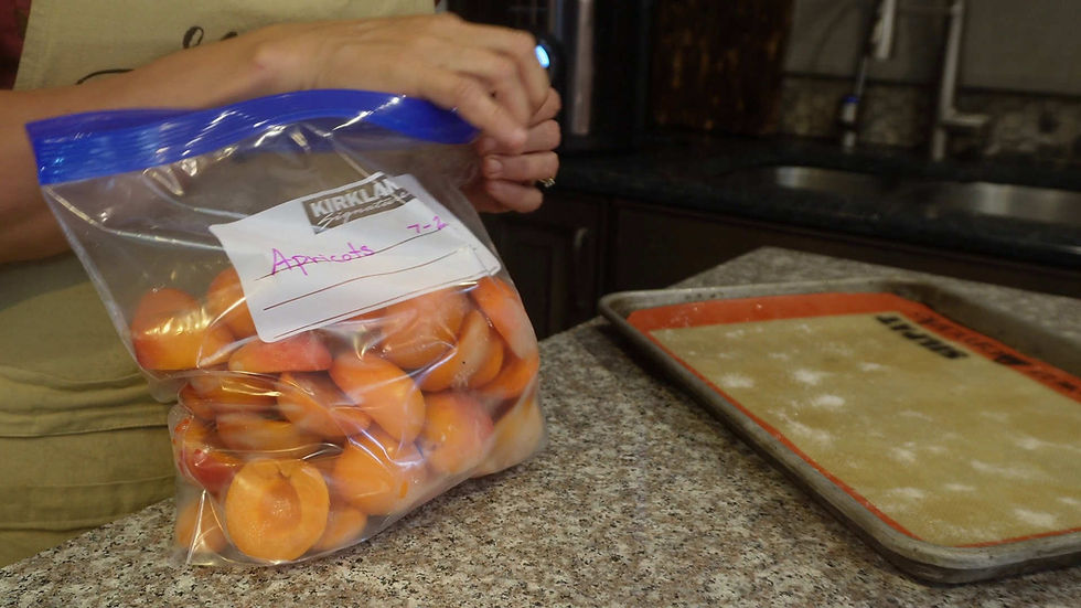 Hands sealing a plastic bag of apricots on a granite countertop next to a baking sheet. Bag labeled "Apricots 7-2" in pink. Kitchen setting.