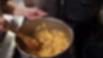 Hands stirring chopped apples in a pot on a stovetop. The kitchen setting is cozy, with a warm, homely atmosphere.