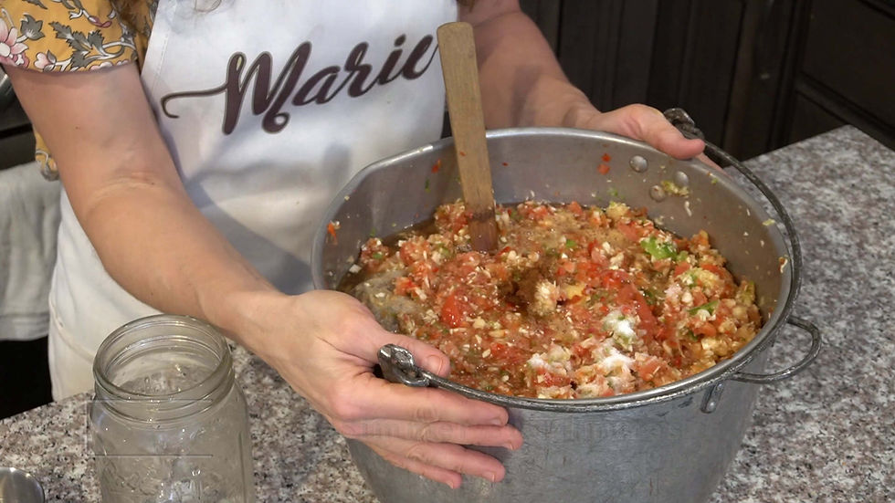 A person in a floral sleeve shirt holds a pot of mixed vegetables with a wooden spoon on a granite countertop. "Marie" is on the apron.