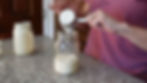 Person in a pink shirt pours liquid into a jar on a granite countertop. Another jar is in the background. Text "Siena" is visible.