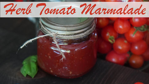 A jar of Herb Tomato Marmalade on a table, surrounded by cherry tomatoes. A green basil leaf is nearby. Rustic and fresh vibe.