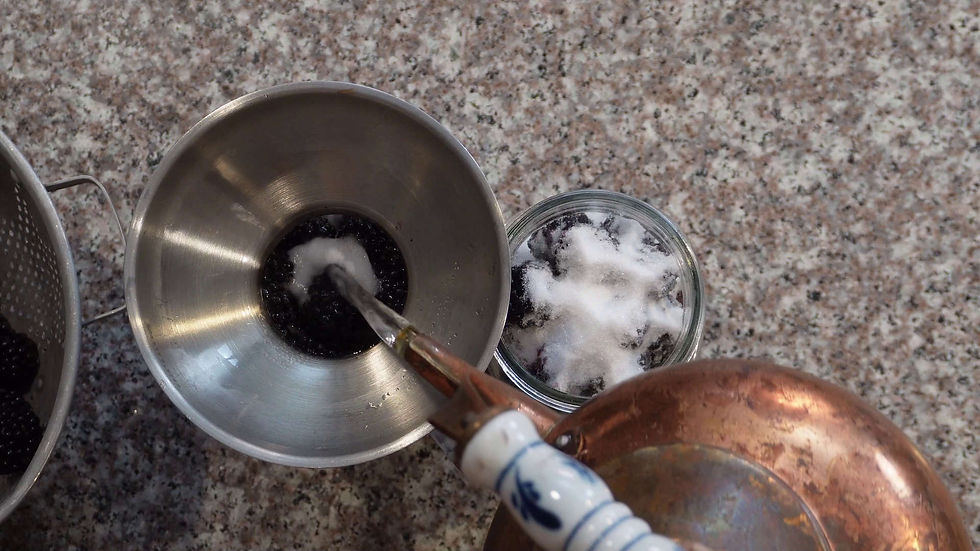 Funnel with blackberries and sugar, colander on left, jar on right. Water pouring from a vintage kettle. Stone countertop background.
