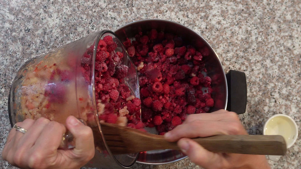 Hands pour frozen mixed berries into a metal bowl on a speckled countertop. A wooden spoon and a small cup are visible nearby.