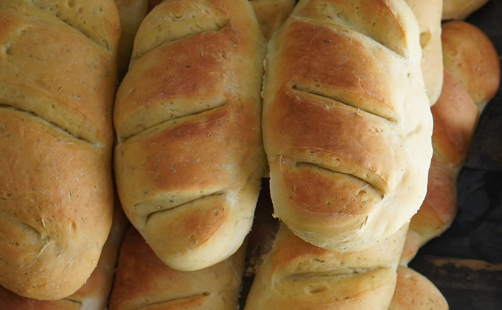 Loaves of fresh, golden-brown bread with slit patterns on a dark background, creating a warm, rustic atmosphere.