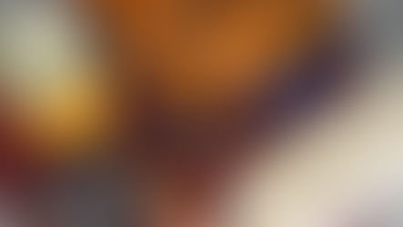 Baked dish with sliced peaches and nuts in a blue tray, jar of peaches, cinnamon sticks, nutmeg, egg, and bread on a red mat.