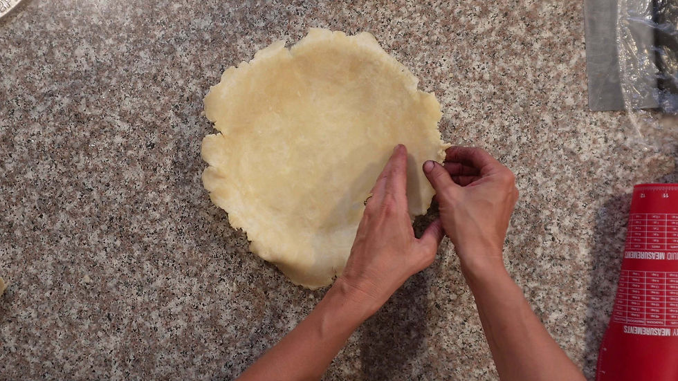 Hands shape pie dough on a speckled countertop. A red measuring mat is visible on the side.