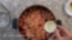 Hand pours water into a pot of mixed berries on a speckled countertop. Text reads: "2 tablespoons Water." Nearby, an empty glass bowl.
