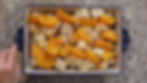 A hand holds a patterned dish with cubed bread and sliced peaches on a granite countertop. The dish has a blue floral design.