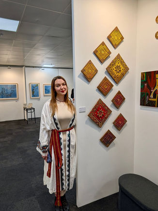 Artist standing beside ceramic wall works at London Art Fair installation