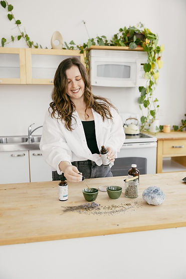 Woman preparing herbal medicine at a table.