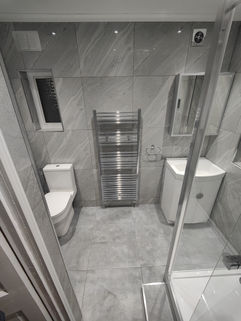 Modern bathroom with toilet, towel rail, vanity unit, and tiled walls in Wembley HA0 3JB renovation