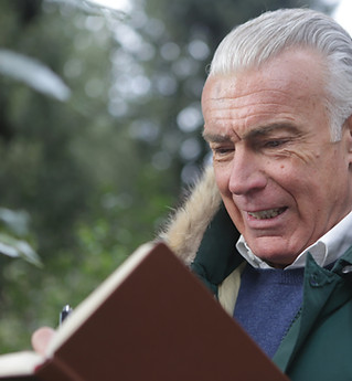 sad-elderly-man-writing-on-brown-noteboo
