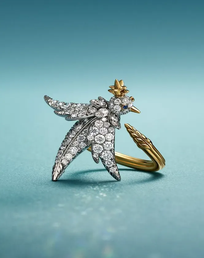 anillo dorado con la forma de un pájaro sobre fondo azul