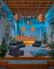 sillones azules oscuros con cojines azules en el suelo, plantas alrededor y luz azul