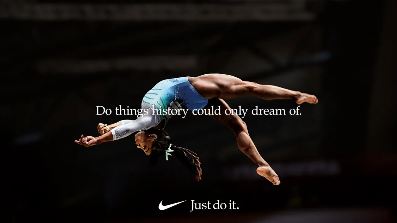 gimnasta vestida de azul y blanco haciendo un salto hacia atrás 