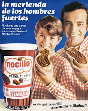 Niño y hombre comiendo una rebanada de pan con novilla. Al frente un tarro de Nocilla sobre una mesa
